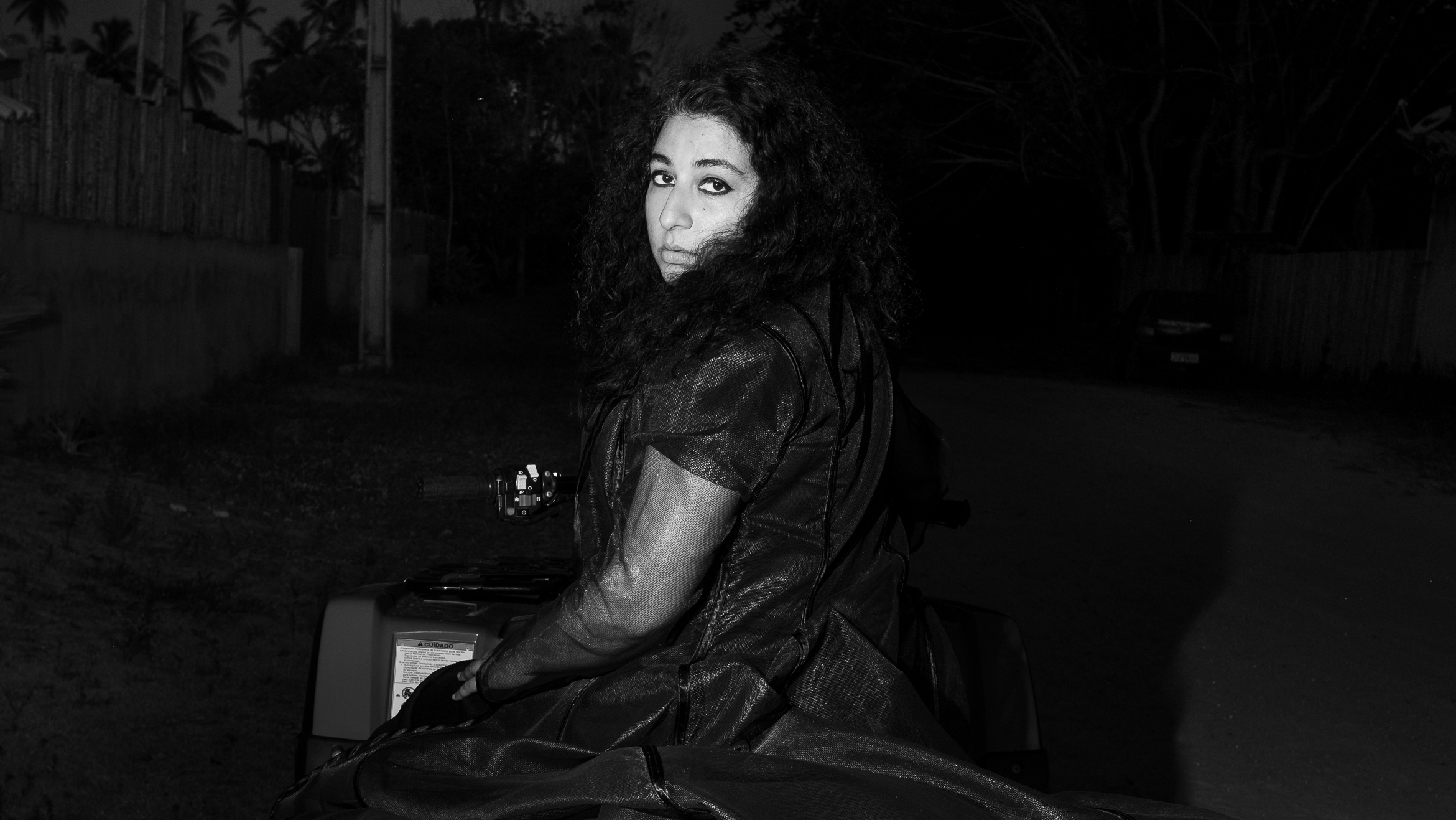 Black and white photo of the artist Arooj Aftab, also a curator for Le Guess Who?, sitting on a motorcycle and looking over her shoulder into the camera